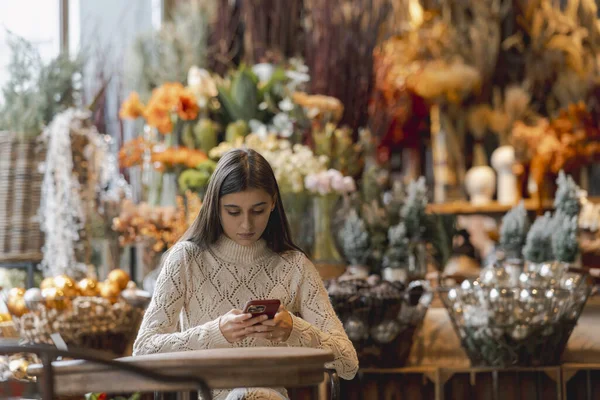 Exploring the decor shop, a young woman holds a phone in her hands. High quality photo