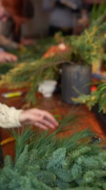 Çam iğneleri, usta bir zanaatkar tarafından Noel çelengi şeklinde şekillendirilir. Yüksek kalite 4k görüntü