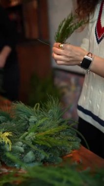 Çam iğneleri, yetenekli bir zanaatkar Noel çelengi yaparken şenlikli bir şekil alır. Yüksek kalite 4k görüntü