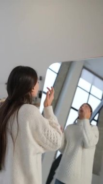 Noel ortamında güzel bir kız aynanın karşısına ustalıkla makyaj yapıyor. Yüksek kalite 4k görüntü