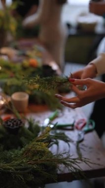 Yetenekli genç bir bayan, bir usta sınıfında Noel çelengi yarattığını gösteriyor. Yüksek kalite 4k görüntü