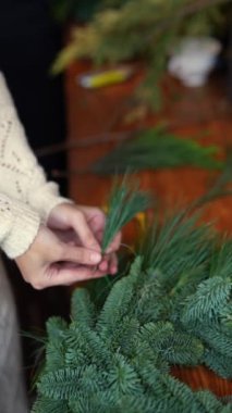 Usta bir zanaatkar, çam dallarını çarpıcı bir Noel çelengine çevirir. Yüksek kalite 4k görüntü