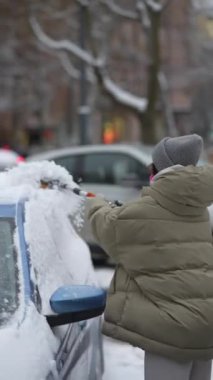 Şehrin sokaklarında, genç bir kadın bir fırçayla karı kaldırma görevini üstleniyor. Yüksek kalite 4k görüntü