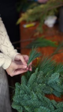 Yetenekli bir zanaatkarın elleri, çam dallarından bir Noel çelengini canlandırır. Yüksek kalite 4k görüntü
