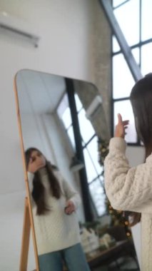 Şenlikli bir toplantıya hazırlanan güzel ve şık bir kadın Noel ağacının yanında kendi bakışını yaratıyor. Yüksek kalite 4k görüntü