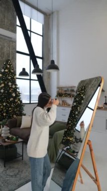 Genç bir kadının aynanın önünde kendini güzelleştirmesi Noel ruhunu yansıtır. Yüksek kalite 4k görüntü