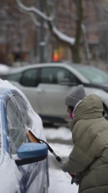 Genç bir bayan otoparkta arabasından kar temizliyor. Yüksek kalite 4k görüntü