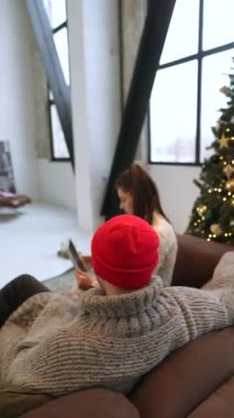 Köpekleri eşliğinde bir çift, Noel ağacının yanında bir tabletle vakit geçiriyorlar. Yüksek kalite 4k görüntü