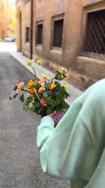 Bir kız elinde bir buket taze çiçekle cadde boyunca yürüyor. Yüksek kalite 4k görüntü