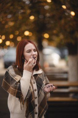 Neşeli kızıl saçlı bir kız sonbahar şehri sokaklarında yürürken mutluluk saçıyor. Yüksek kalite fotoğraf