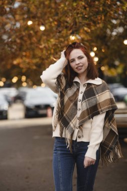 Sonbahar şehrinin sokaklarında neşe saçan neşeli bir kızıl. Yüksek kalite fotoğraf