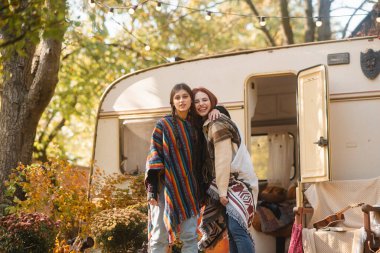 Hippi kıyafetli iki şık kız bir karavanın arka planında poz veriyor. Yüksek kalite fotoğraf