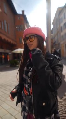 Göz kamaştırıcı genç bir kadın elinde telefonuyla güneşli bir İtalyan şehrini keşfediyor. Yüksek kalite 4k görüntü