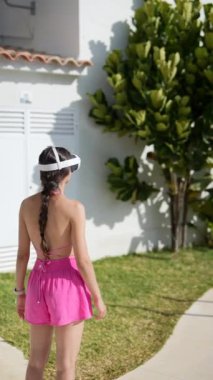 Pembe elbiseli bir kadın güneşli bir günde havuz kenarında güneşleniyor ve sıcak havanın tadını çıkarıyor.