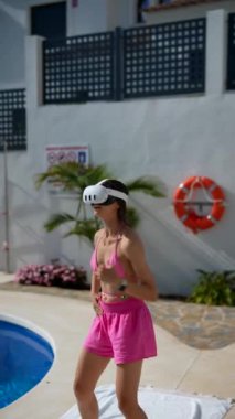 Bir kadın yaz boyunca havuz kenarında sanal gerçeklik deneyiminin tadını çıkarıyor. Açık hava ortamında eğleniyor.