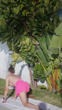 Pembe şortlu bir insan, yemyeşil bitkiler ve canlı yeşilliklerle çevrili havuzda rahatlar.