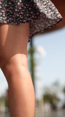 Çiçekli bir elbisenin altında, rüzgarda dalgalanan kaygısız güzellik ve zarafet saçan bir kadının bacaklarının yakın çekimi.