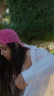 Pembe şapkalı genç bir kız mutlu bir şekilde dışarıda oynuyor, doğa ile çevrili, kaygısız ve neşeli bir anın tadını çıkarıyor.