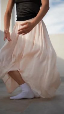 Zarif dans eden genç bir kadın siyah bluzlu ve dalgalı etekli poz veriyor, terasta gösteri yapıyor..