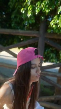 Pembe şapkalı genç bir kız açık havada eğleniyor, güneşli bir günde birçok açıdan yakalandı..