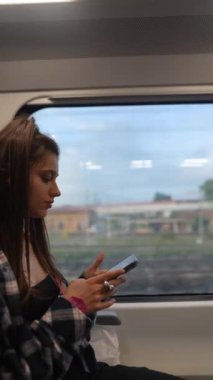 Trendeki genç bir kadın akıllı telefonuyla farklı açılardan görülen modern şehir seyahatini resmediyordu.