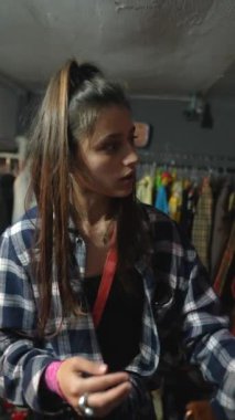 At kuyruklu genç bir kadın modaya uygun bir butikte çeşitli kıyafet seçeneklerini gözden geçiriyor.