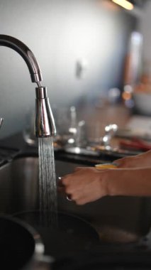 Şık, modern bir mutfak lavabosunda akan bir musluğun altında el yıkamayı gösteren ayrıntılı bir an.