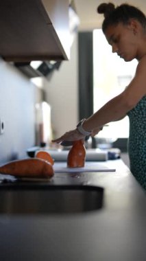 Genç bir kadın modern bir mutfakta ustalıkla tatlı patatesleri dilimliyor, mutfak uzmanlığını sergiliyor.