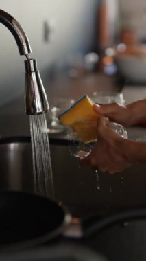 Mutfak lavabosunda akan suyun altında süngerle bardağı yıkayan eller temizliği ve günlük işleri ön plana çıkarıyor..