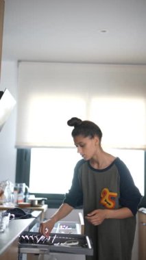 Genç bir kadın modern bir mutfakta yemek hazırlıyor, günlük kıyafetler giyiyor ve mutfak tezgahında çalışıyor..