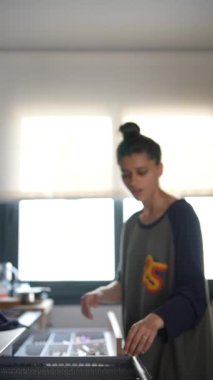 Genç bir kadın modern bir evde mutfak çekmecesini mutfak eşyalarıyla verimli bir şekilde düzenliyor..