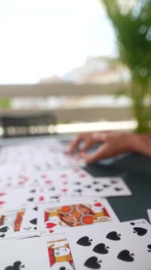 Eller ustalıkla bir açık masa üzerinde iskambil kağıtlarını düzenliyor ve arka planda yumuşak bulanıklık yaratıyor.