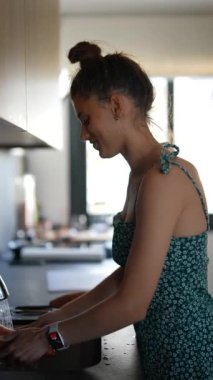 Genç bir kadın, modern bir mutfakta sebzeleri temizliyor ve sağlıklı gıda hazırlıklarına odaklanıyor.