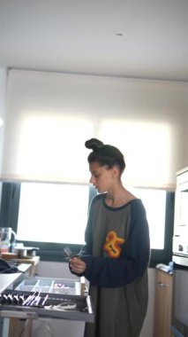 Modern bir mutfakta, rahat genç bir kadın mutfak aletleri düzenler, günlük yaşam için düzenli ve düzenli bir ev alanı yaratır.