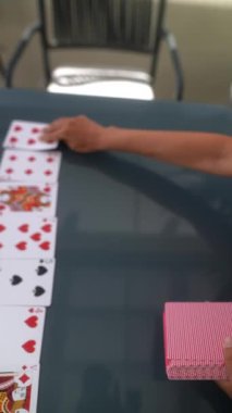 Bir dizi iskambil kağıdı, kalp ve maça da dahil, bir el dağıtım kartlarıyla cam bir masanın üzerine serilmişti..