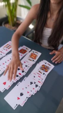 A woman spreading a deck of cards on a table, captured in various frames, showcasing a card game setup.