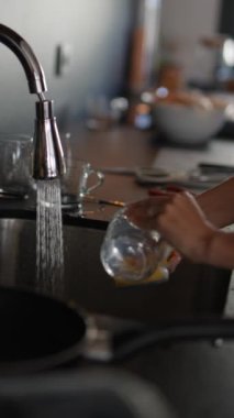 Çalışan bir mutfak musluğunun altında bulaşıkları yıkayan, düzenli ve düzenli ev işleri yapan ellerin yakınlığı