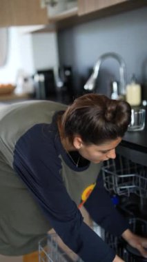 Mutfak dolaplarında günlük giysiler içinde bulaşık düzenleyen bir kadın. Ev işleri ve ev hayatı konsepti.