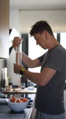 Çağdaş bir mutfakta, genç bir adam tatlı patatesleri tuzla tatlandırır ve kendini aşçılığa adadığını gösterir.