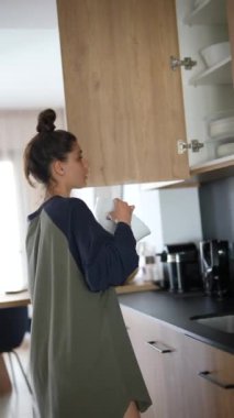 Bir kadın mutfağını düzenlemekle, bulaşık makinesini yüklemekle, dolapları düzenlemekle, evini düzenli tutmakla meşgul.
