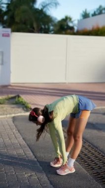 Kulaklıklı bir kadın dışarıda egzersiz yapıyor, koşuyor, spor kıyafetlerini giyiyor, sağlıklı bir yaşam tarzını destekliyor.