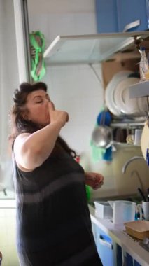 Mutfakta meşgul bir kadın, taze ürünlerle ev yapımı yemeğe odaklanıyor, evde mutfak işi yapıyor.