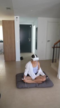 Bir kadın modern bir evde VR kulaklık kullanıyor, sakin ve engin bir deneyim için günlük kıyafetler giyiyor.