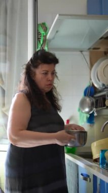 Mutfakta yemek hazırlayan bir kadın, günlük ev işleri ve ev yapımı sorumluluklarını yansıtıyor.