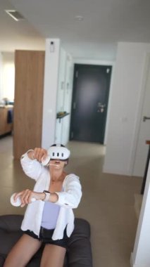 Bir kadın, bir yastığın üzerinde diz çökerken sanal gerçekliğe bir VR kulaklığı ve kontrolörle daldırılır..