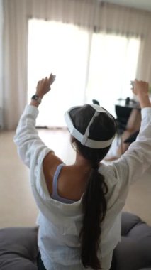 Sanal gerçeklikte oyun oynamak ve kendini kaptırmak için VR kulaklık ve kumanda kullanan bir kadın.