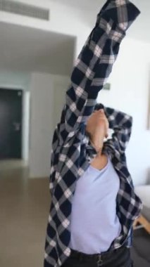 Genç bir kadın şık dekorlu, modern bir yaşam alanında canlı dans yeteneklerini sergiliyor.