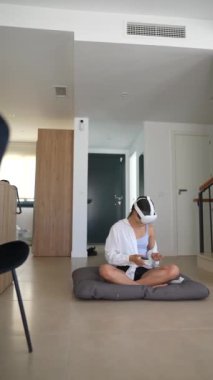Bir kadın modern bir iç mekanda geçirdiği deneyimden dolayı VR kulaklığını ve kontrolörlerini sever.