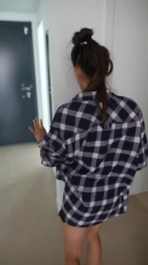 Bir kadın gündelik giysiler içinde enerjik bir şekilde dans eder, serbest stil harmanlayarak modern bir evde rahat ve eğlenceli bir atmosferde hareket eder.