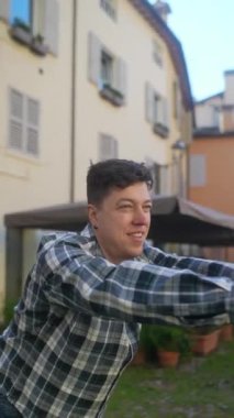 Ekose gömlekli genç adam, tuhaf bir avluda eğleniyor, fiziksel aktivitelerle meşgul..